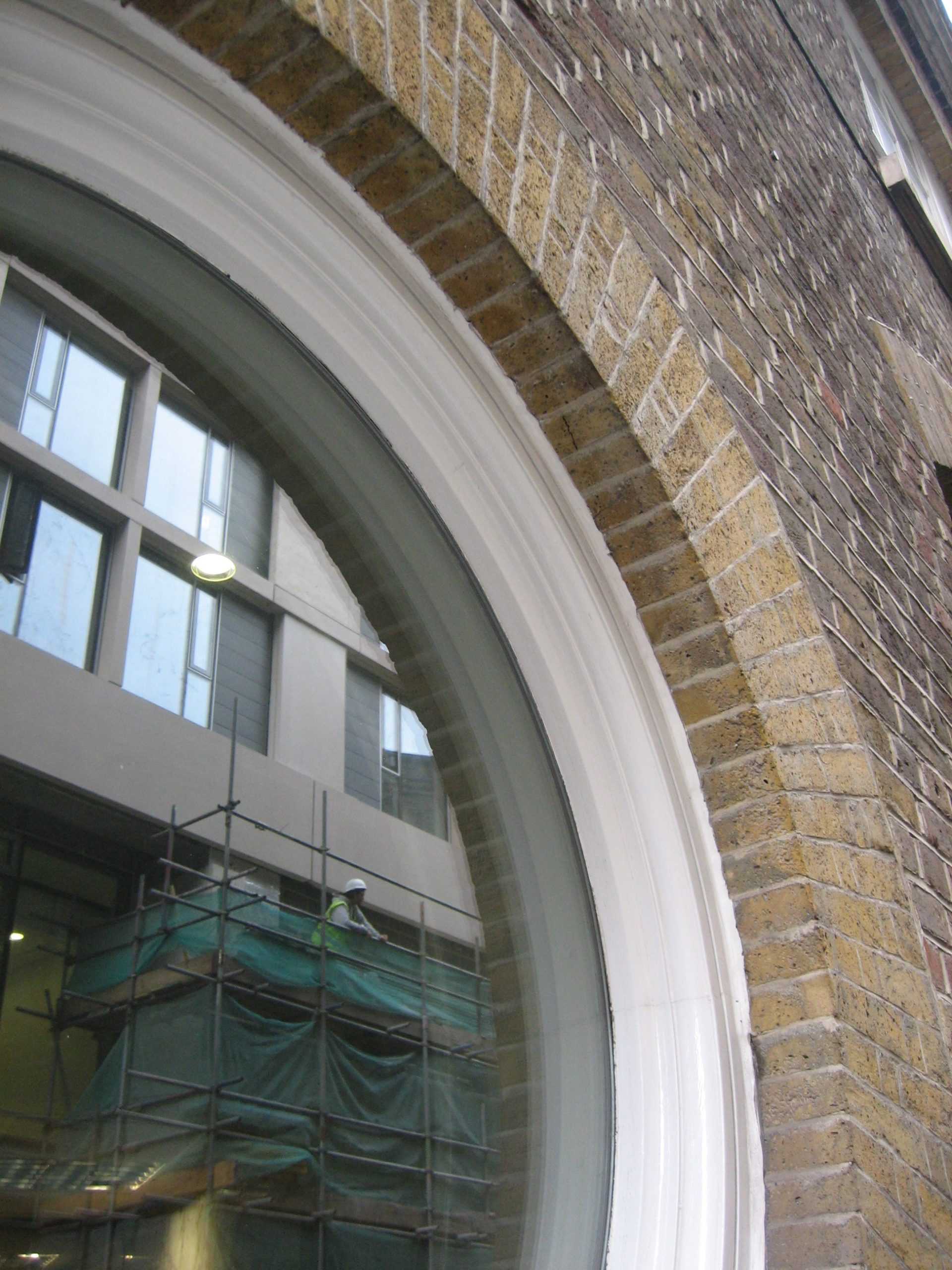 Close up of round window with white frame and yellow bricks