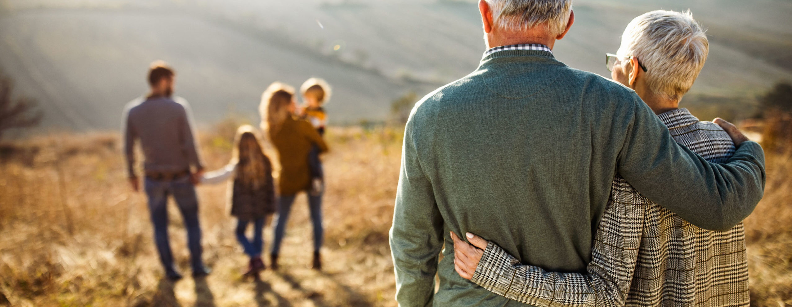 Joyful multigenerational family moment with grandparents watching their family on a walk representing happy retirement and family values.