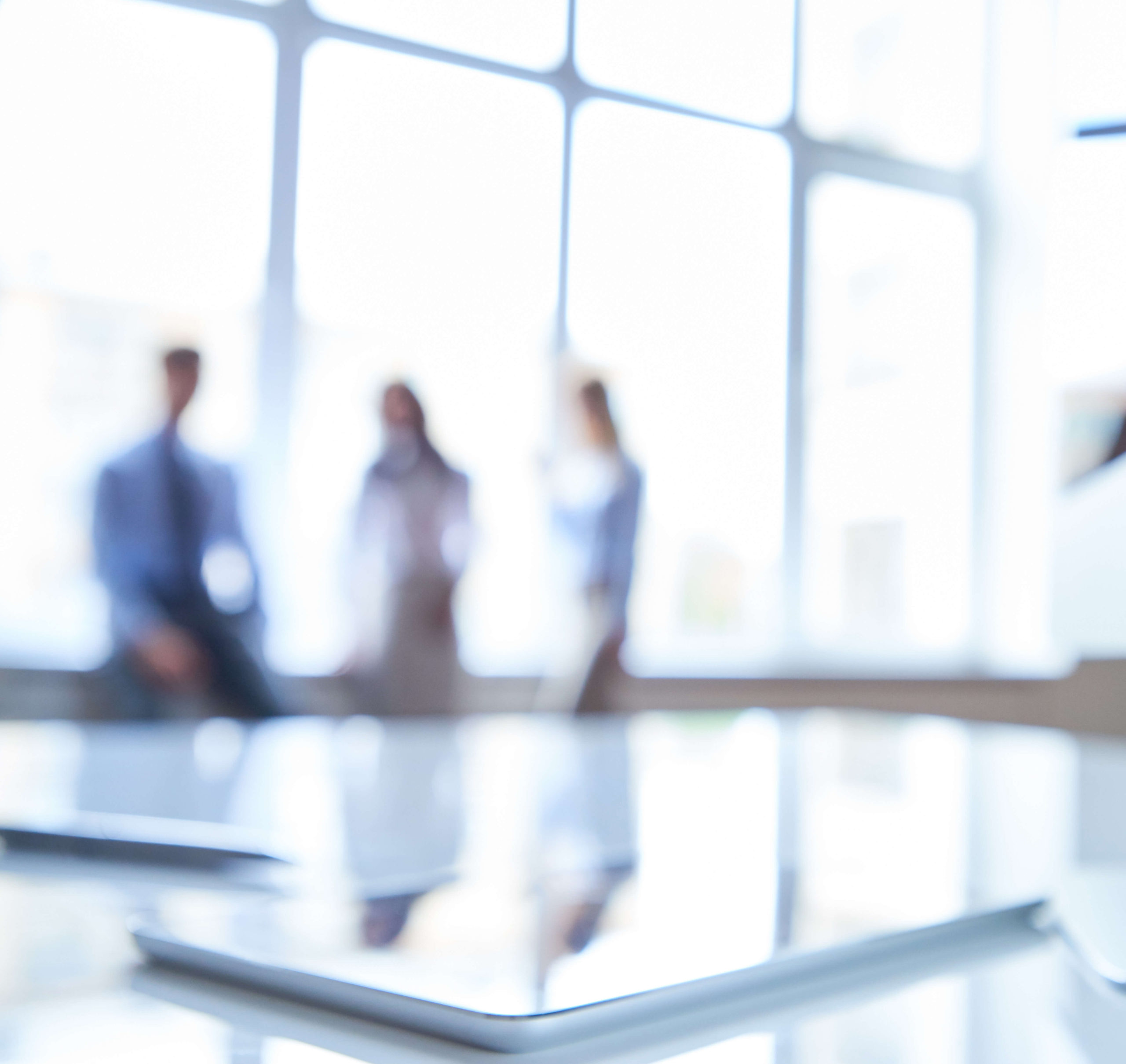 Contemporary corporate office environment with focused, blurred view of business professionals in a bright, modern workspace, denoting strategic planning.
